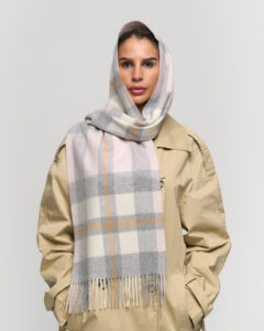 A professional styling shot of an oversized cashmere stole worn as a wrap, perfect for international festival travel.